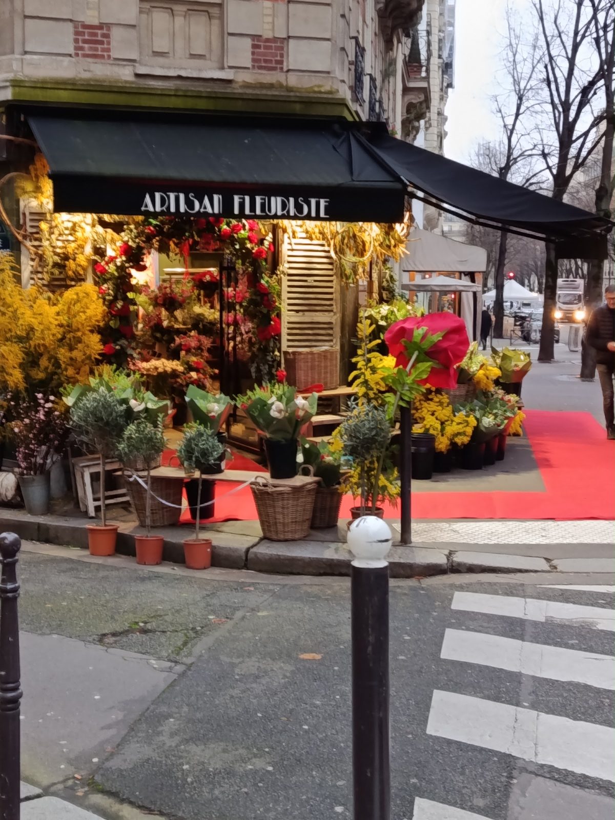 La devanture du 107 avenue Mozart, store noir « Artisan fleuriste » et fleurs sur le trottoir